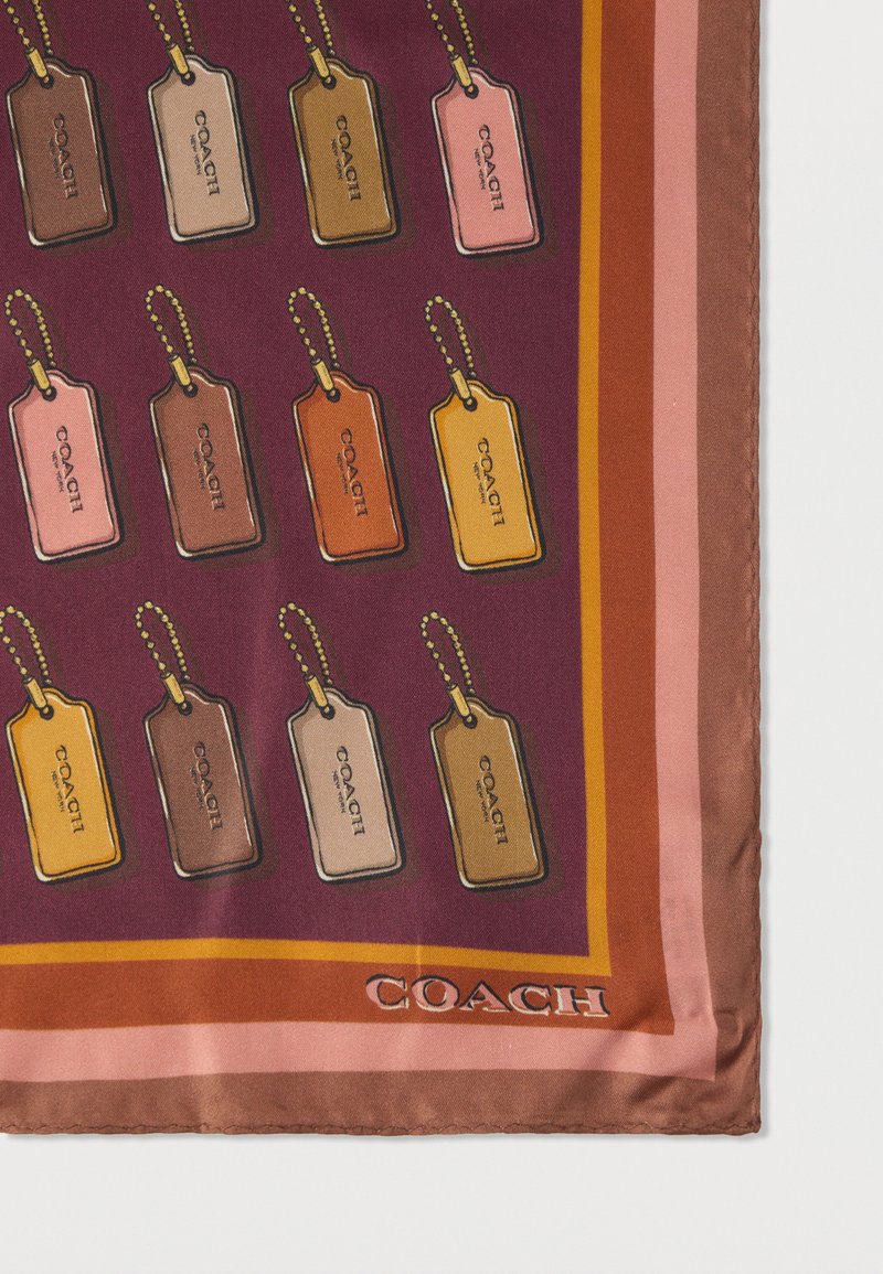 Sciarpa di seta con colorati tag per bagagli in sfumature di rosa, marrone e giallo su uno sfondo viola, con un bordo marrone a contrasto e il marchio "COACH".
