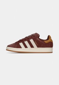 Bordeaux ruskinds sneakers med hvide læderstriber, en gummirubsål, rund toe og en tan accent ved hælen. Gyldent "CAMPUS" branding.