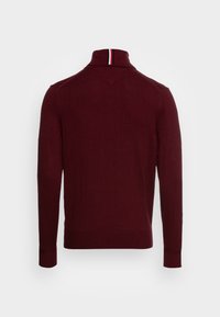 Bordeauxfärgad stickad tröja med hög krage, ribbade muddar och en kontrasterande randig accent vid kragen. Slät textur med en elegant design.