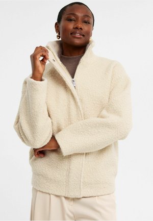 Cremfarbener, wuscheliger Fleece-Jacke mit hohem Kragen, Reißverschluss und lockerer Passform. Verfügt über einen strukturierten Stoff mit breiten, weichen Ärmeln.