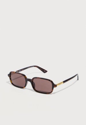 Rectangular tortoiseshell sunglasses with brown lenses and gold accents on the temples, resting on a white surface.