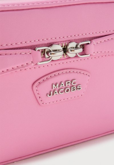 Κοντινό πλάνο ροζ δερμάτινης τσάντας με ασημένιο φερμουάρ και λογότυπο Marc Jacobs σε ραμμένη ετικέτα.