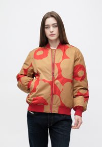 Brązowo-czerwona kurtka typu bomber z dużym kwiatowym wzorem, elastycznymi mankietami i paskiem w talii, posiadająca przedni zamek błyskawiczny oraz boczne kieszenie.