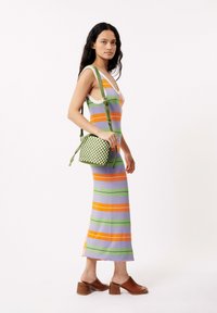 Ärmelloses gestreiftes Kleid in Lavendel-, Orange- und Grüntönen, kombiniert mit einer grün karierten Handtasche und braunen Blockabsatzsandalen.