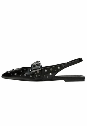 Czarny, spiczasty, płaski but typu slingback z srebrną klamrą i okrągłymi metalowymi ćwiekami na cholewce i pasku.
