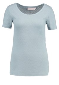 Ljusblå stickad topp med kort ärm och rundad halsringning, med ett texturerat mönster som har små prickar över hela tyget.