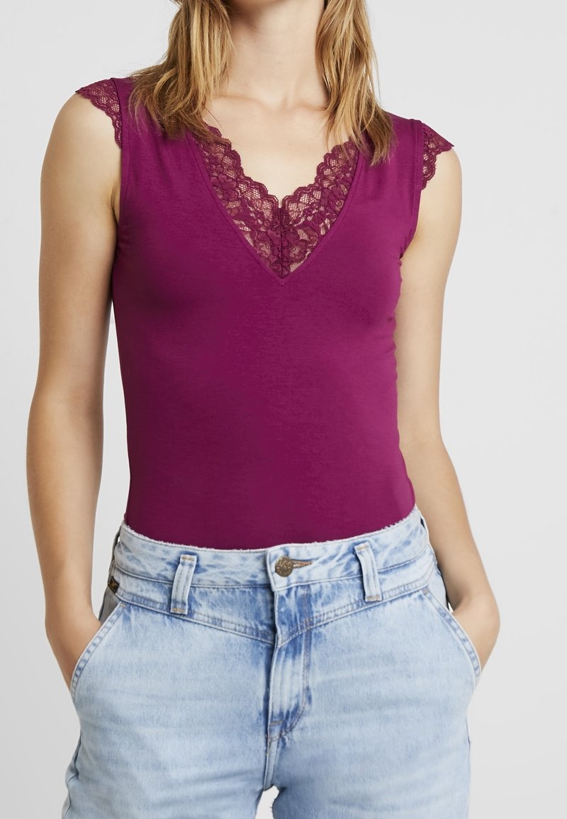 Bodysuit en ciruela oscuro con mangas cortas de encaje y un escote pronunciado con ribete de encaje, combinado con pantalones cortos de denim de cintura alta en azul claro.