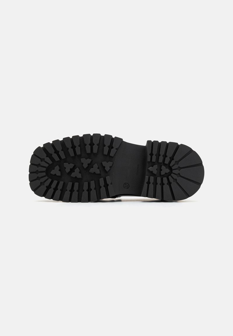 Suola di scarpa in gomma nera con un design di battistrada spesso e texture, caratterizzata da scanalature profonde e motivi multidirezionali per una maggiore aderenza.