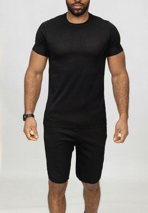 T-shirt noir à manches courtes côtelées et short assorti, fabriqué en tissu extensible, design ajusté, texture visible, lignes épurées.