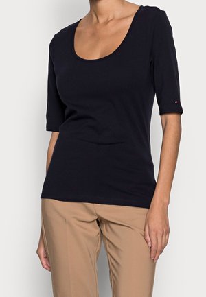 Schwarzes T-Shirt mit kurzen Ärmeln und Rundhalsausschnitt, aus glattem Stoff gefertigt. Verfügt über ein kleines Logo-Detail am Ärmel.