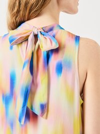 Μάλλινο τοπ χωρίς μανίκια σε πολύχρωμο σχέδιο tie-dye με αποχρώσεις του μπλε, ροζ, κίτρινου και λευκού; διαθέτει λεπτομέρεια με φιόγκο στη φυσούνα στο πίσω μέρος.