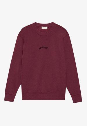 Sudadera de cuello redondo burdeos, hecha de algodón, con mangas largas y un pequeño logo bordado en negro en el pecho. Textura suave.