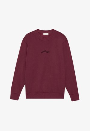 Sudadera de cuello redondo burdeos, hecha de algodón, con mangas largas y un pequeño logo bordado en negro en el pecho. Textura suave.