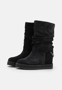 Černé kotníkové boty z broušené kůže s volným designem, tlustou platformovou podrážkou s pleteným detailem a malým kovovým řetízkovým akcentem na zadní straně.