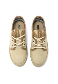 Baskets en toile beige avec des accents en cuir brun, bout rond, lacets blancs épais et semelle en corde tressée. Marque visible sur la languette.