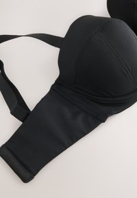 Reggiseno nero imbottito con spalline regolabili e fascia inferiore larga, steso su sfondo chiaro.