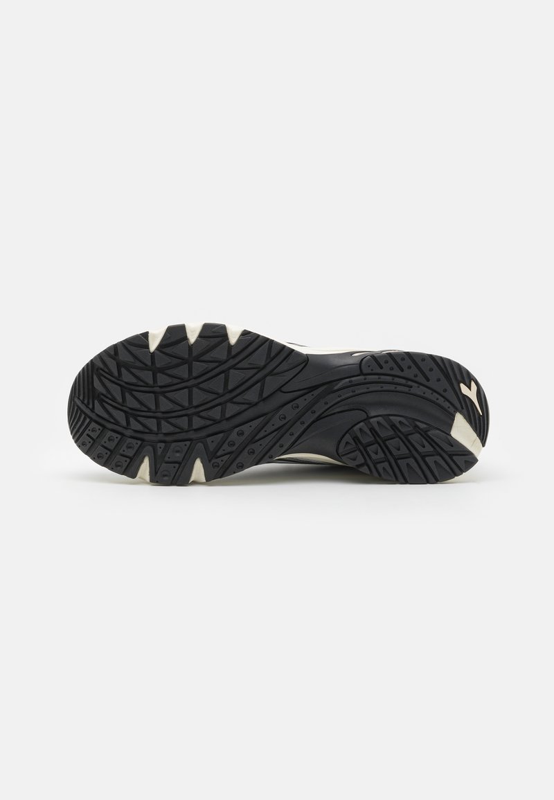 Suola di scarpa con fondo in gomma nera e motivi testurizzati per una migliore aderenza, dettagli bianchi e un design del battistrada multi-direzionale per trazione.