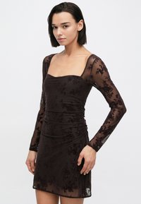 Braunfarbenes Kleid mit langen, transparenten Ärmeln, quadratischem Ausschnitt, floralem Muster, gerafftem Körper und kurzem Saum, gefertigt aus leichtem, dehnbarem Material.