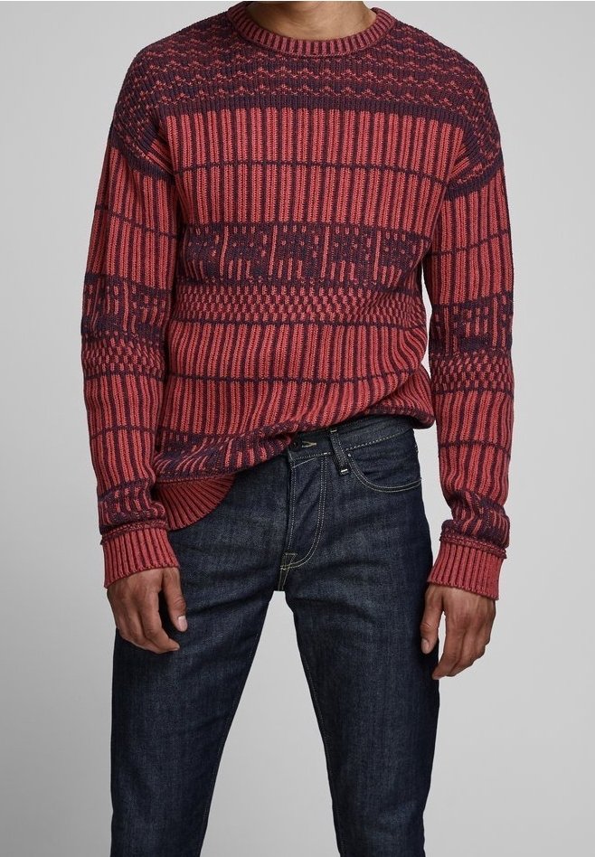 Rot-navy gemusterter Strickpullover mit rundem Ausschnitt und gerippten Bündchen, kombiniert mit dunkelblauen Jeans. Ganzflächiges strukturiertes Design.