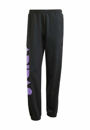Zwarte trainingsbroek met een relaxed fit, met een groot paars "ADIDAS" logo op het linkerdij en elastische boorden bij de enkels. Gemaakt van zachte stof.