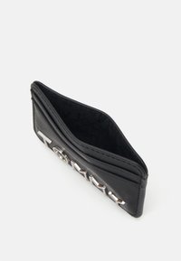 Černá kožená peněženka na karty s reliéfním logem, štíhlý design, dvě sloty na karty a strukturovaný povrch. Interiér podšitý látkou s vzorem značky.