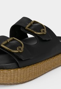 Μαύρο δερμάτινο σανδάλι με δύο ρυθμιζόμενες χρυσές αγκράφες και πλεκτή ταμπά σόλα πλατφόρμας.