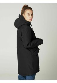 Juoda, su gobtuvu striukė, pasižyminti lygiu paviršiumi, priekinėmis kišenėmis ir ilgu dizainu. Nėra matomų logotipų ar išskirtinių raštų.