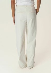 Light cream wide-leg trousers with a clean design, featuring two back pockets and smooth, wrinkle-resistant fabric.