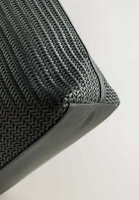 Schwarze geflochtene Tasche mit strukturiertem Außenmaterial und glattem Lederboden. Besitzt eine strukturierte Form mit auffälligen Nähten an den Kanten.