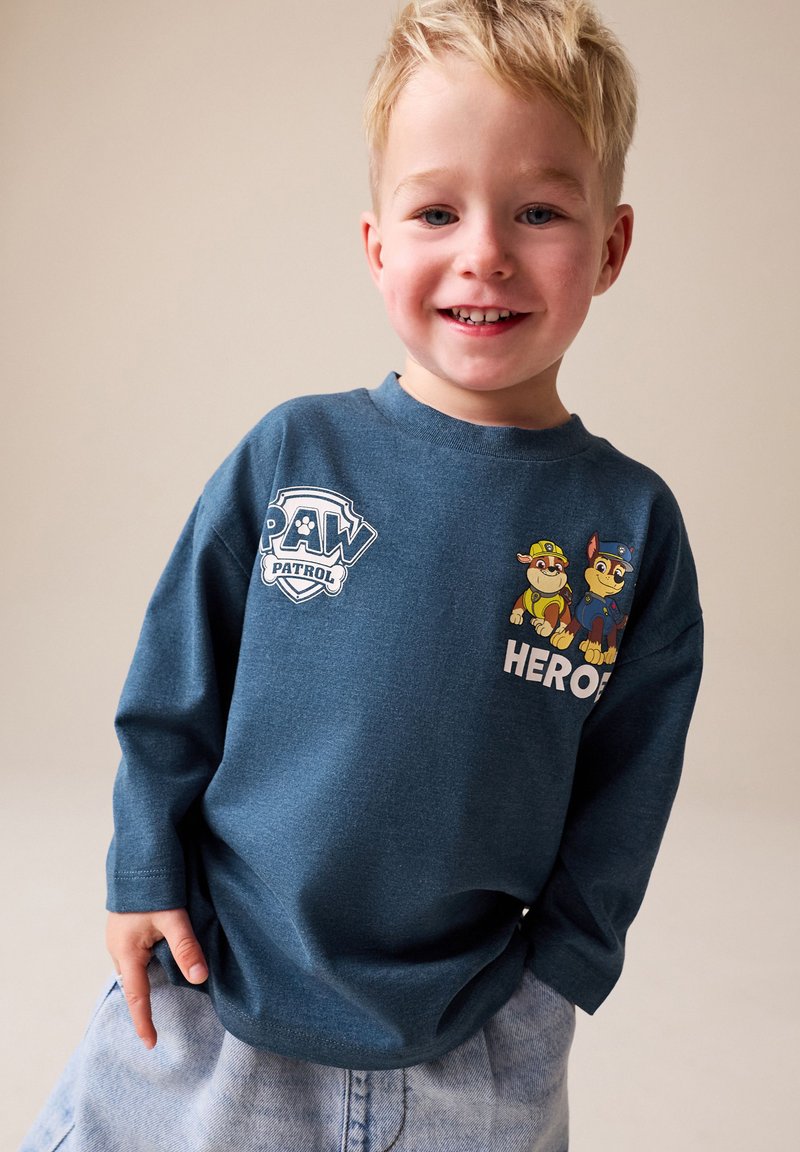 Zils kokvilnas T-krekls ar garām piedurknēm, uz priekškara attēlots "PAW Patrol" logotips un multfilmu varoņi, ar brīvu piegriezumu un teksturētu audumu.