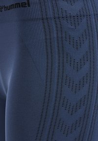Granatowe legginsy z teksturowanym wzorem, zawierające pionowe linie i wzory w kształcie chevronu, wykonane z elastycznego, odprowadzającego wilgoć materiału.