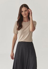 Haut beige à manches courtes associé à une jupe bleu marine à motif floral, en tissu doux, coupe décontractée et encolure ronde.