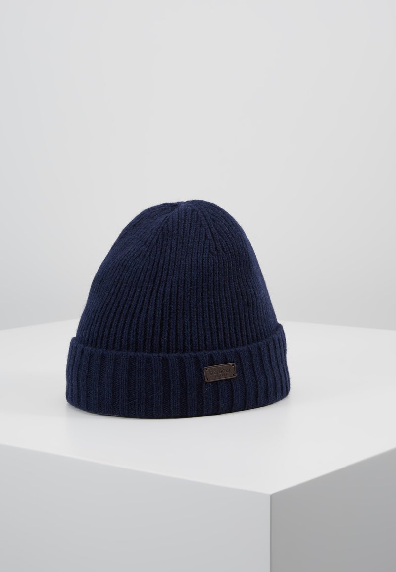 Knitted navy beanie with a ribbed design and a folded brim. Features a small, dark brown label on the front. Soft texture.