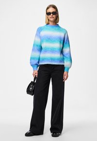 Knit sweater featuring a gradient of blue and teal stripes, round neckline, and long sleeves. Paired with black wide-leg trousers and handbag.