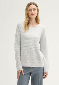 Lichtgrijze trui met een visgraatmotief, brede halslijn, lange mouwen en een lichtroze onderrand. Zachte textuur en ruime pasvorm.