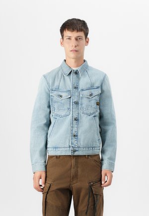 Lichtblauwe denimjack met een knoopsluiting aan de voorkant, twee borstzakken en een puntige kraag. Heeft een cropped zoom en een gestructureerde stof.