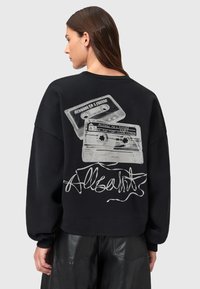 Felpa nera con vestibilità oversize, presenta una grafica di due cassette e la scritta "Allsaints" sul retro. Tessuto morbido, design semplice.