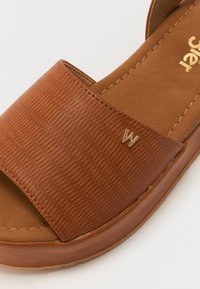 Brune sandaler med glidende såle, med en teksturert overdel, en glatt matt overflate og en subtil metallisk logoaktsent. Polstret fotseng for komfort.
