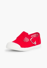 Zapatilla de lona roja con una suela de goma blanca, que cuenta con una correa con un hebilla de plata y un forro de tela a cuadros.