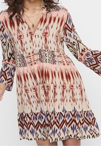 Vestido de estampado multicolor con mangas largas y escote en V. Confeccionado en tela suave con detalles de volantes en capas y motivos tribales.