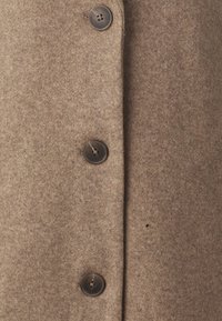 Bruine wollen jas met vijf ronde knopen in donkerbruin, textuurstof en een gladde afwerking met subtiele details.