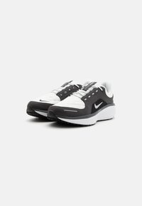Nike-Laufschuhe mit einem schwarz-weißen Farbschema. Verfügt über ein gesteppte Obermaterial, gepolsterten Kragen und eine strukturierte Gummisohle für besseren Halt.