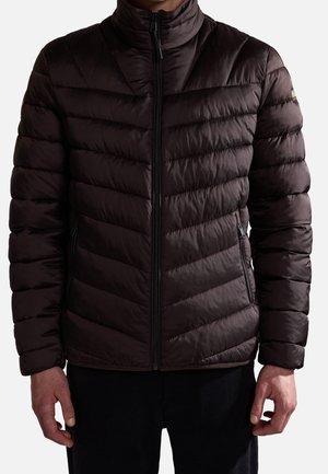 Mann trägt eine dunkelbraune, gesteppten Reißverschlussjacke mit diagonalen Nähten und seitlichen Reißverschlusstaschen.