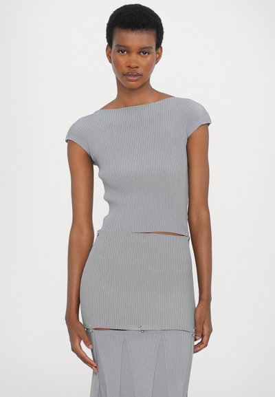Vestido de punto gris con canalé y mangas cortas, que presenta un top corto, cintura ceñida y acentos metálicos decorativos en las costuras.