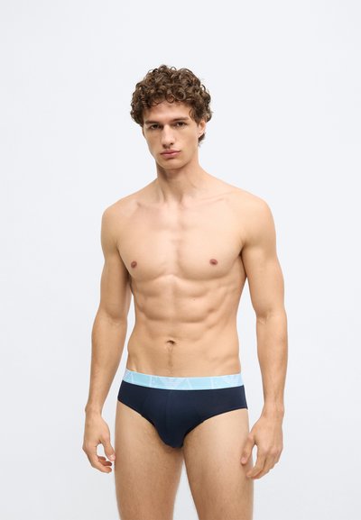 Cuecas de algodão azul-marinho com um cós elástico azul-claro apresentando um logótipo. O design é ajustado, com uma textura suave e costuras mínimas.