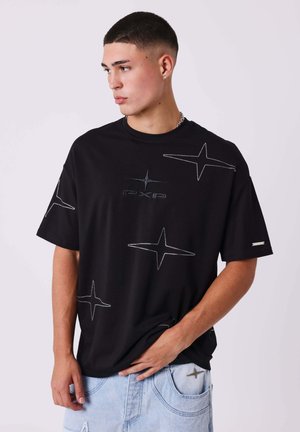 Camiseta de manga corta negra con diseños en forma de estrella y logo bordado. Fabricada en algodón con un corte holgado, presenta un escote redondo y costuras visibles.