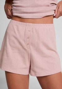 Lichtroze katoenen shorts met een gestructureerd patroon, een relaxte pasvorm en drie tonale knopen aan de voorkant. Elastieken tailleband voor comfort.