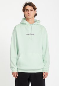 Licht mintgroene hoodie met een kangoeroe zak, capuchon en trekkoorden; voorzien van een paarse "VOLCOM"-logo op de borst.