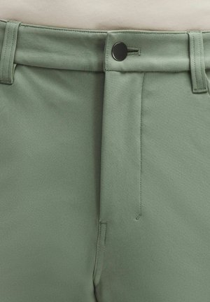 Lähivõte salvei-rohelisest püksipaarist, millel on must nupp, vööaasad ja peidetud lukuga eesmine eesmine osa.