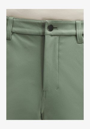 Lähivõte salvei-rohelisest püksipaarist, millel on must nupp, vööaasad ja peidetud lukuga eesmine eesmine osa.